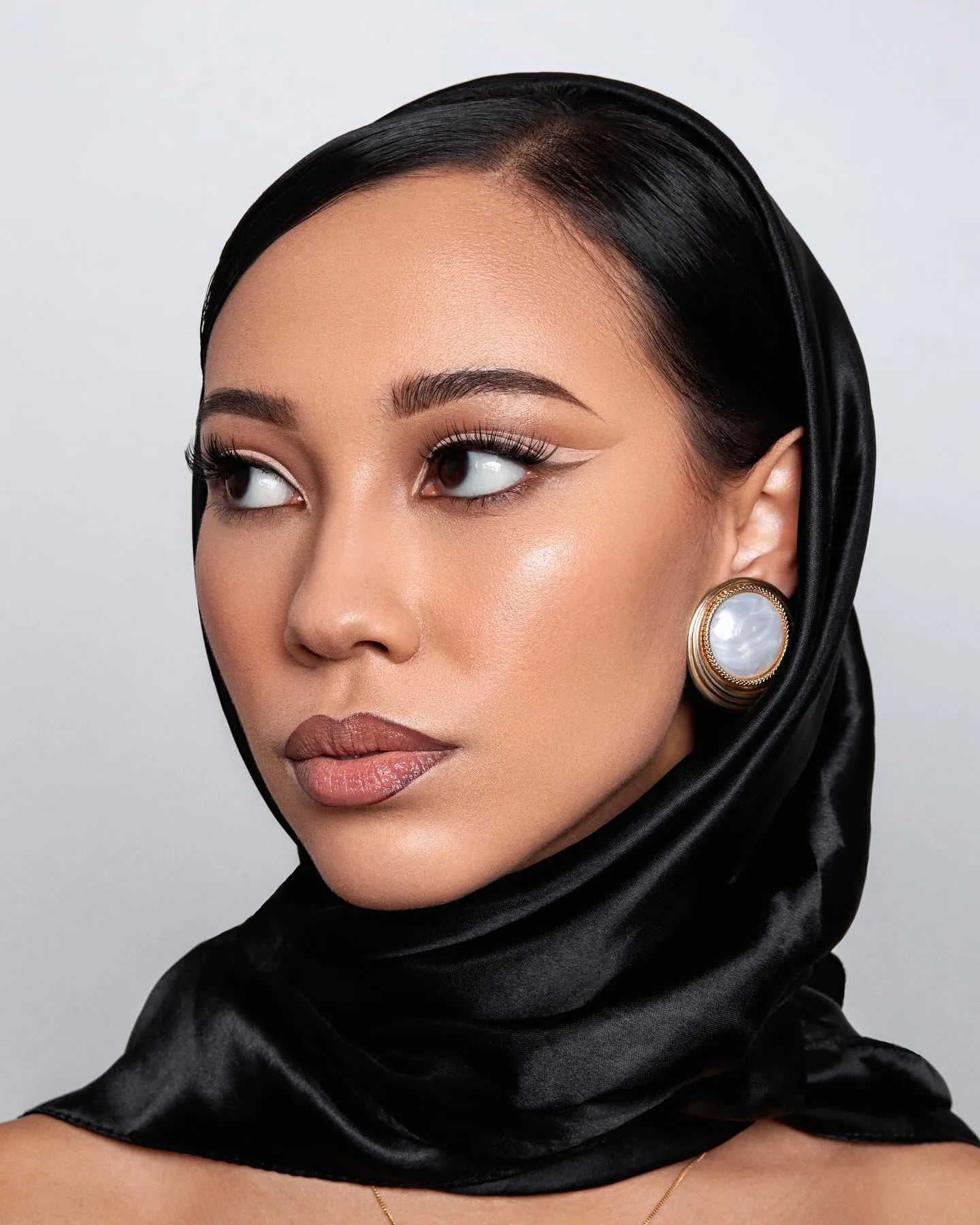 Klassieke look: zwarte satijnen hoofddoek, nude eyeliner, volle wimpers en bruinroze lippen