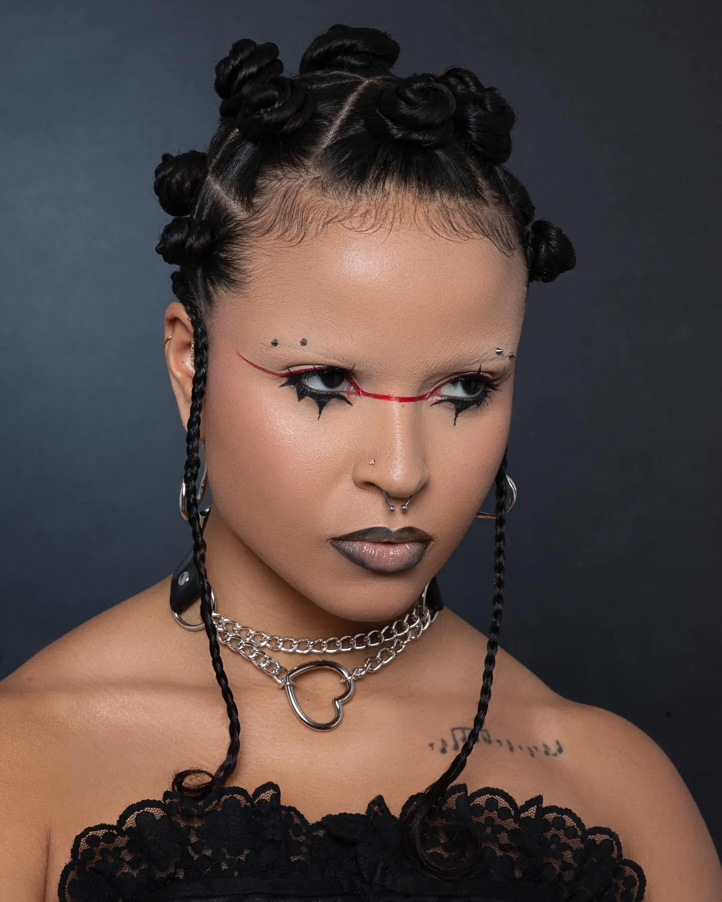 Afro punk-look: bantu knots, rode grafische lijn over de neus, zwarte gepunte eyeliner en grijze lippen