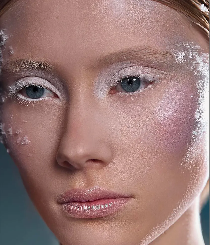 Beauty close-up met ijskristallen op de huid, witte wimpers en roze blush