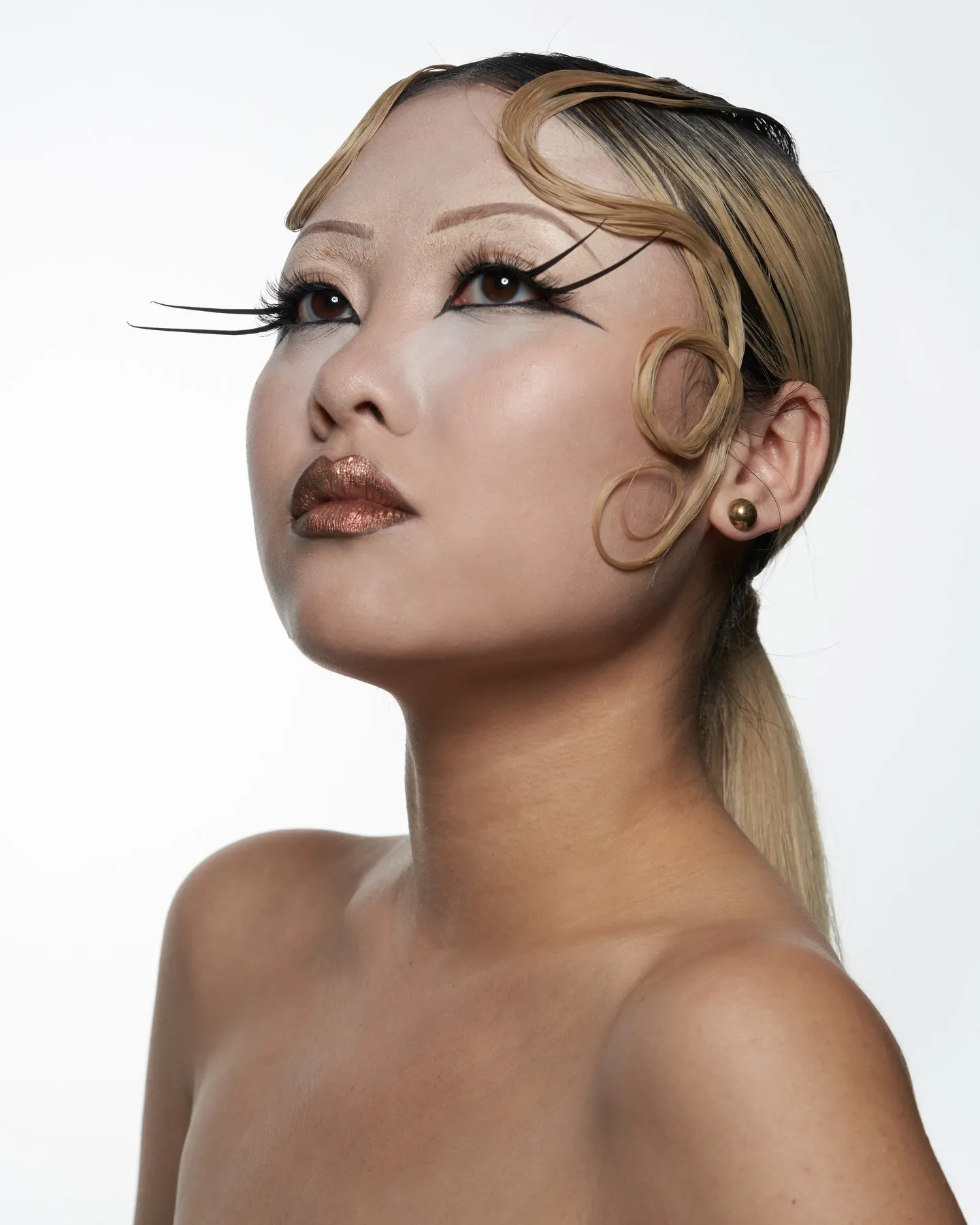 Editorial look met zelfgemaakte extra lange wimpers, gebeeldhouwde blonde krullen en bronzen glitterlippen