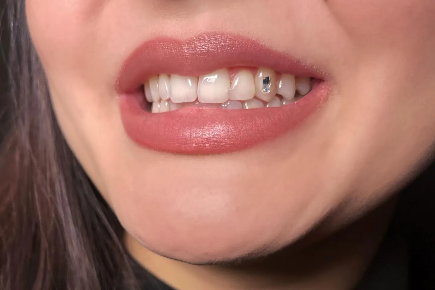 Rechthoekig kristal als tooth gem op een snijtand, roze lippen en zwarte coltrui